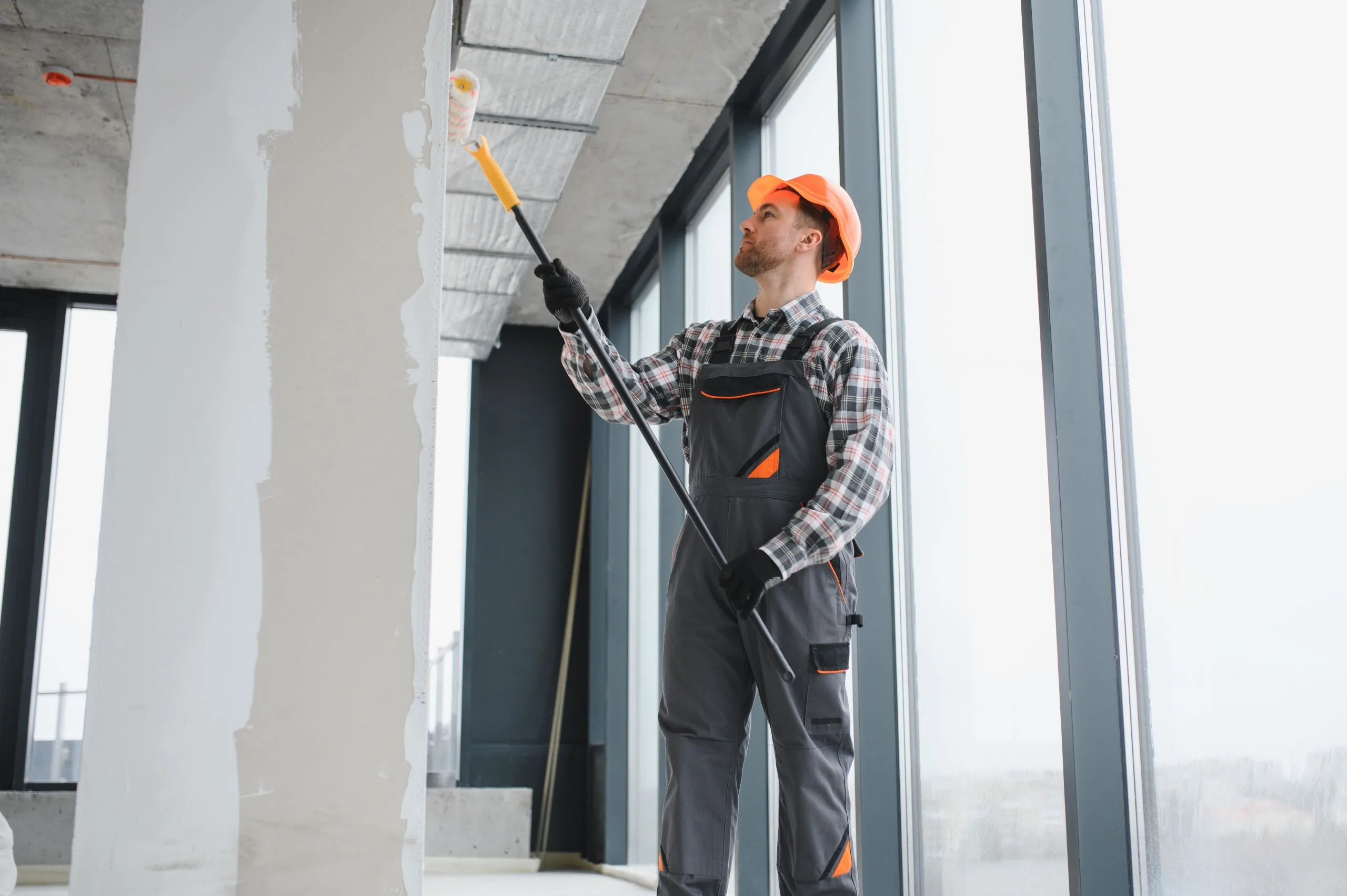 Commercial painter in hardhat painting structural column in multi-story office building by Bos-Flo Coatings