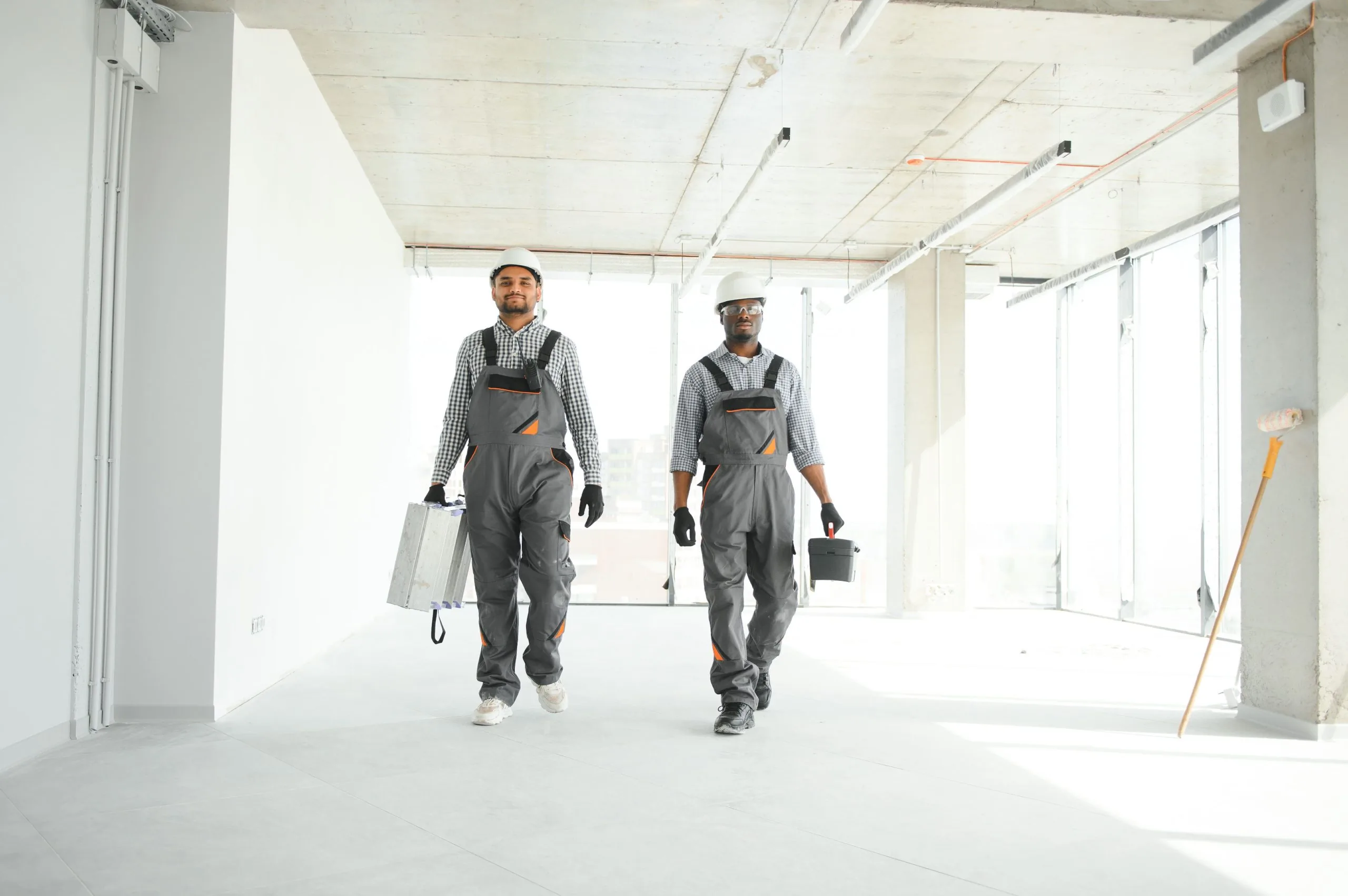 Two professional painters in hardhats walking through freshly painted commercial interior by Bos-Flo Coatings