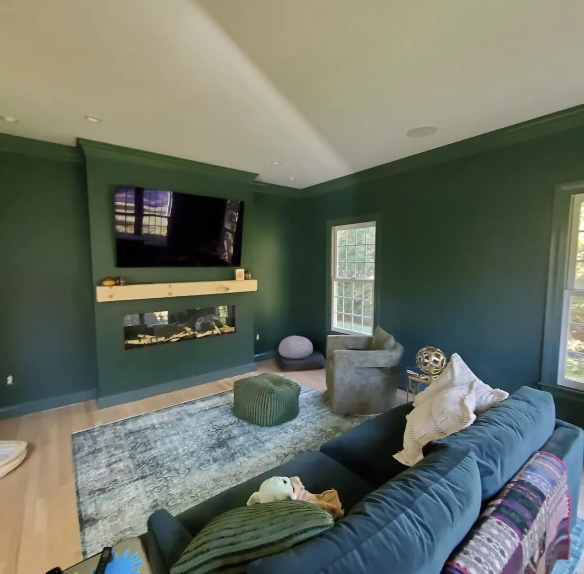 Living room painted in rich emerald green with crown molding and modern fireplace by Bos-Flo Coatings