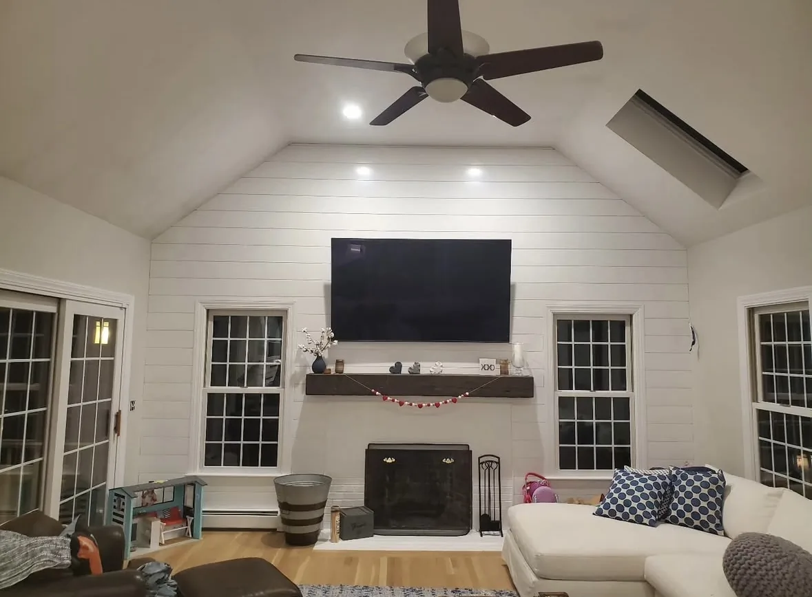 Living room with painted white shiplap accent wall and vaulted ceiling by Bos-Flo Coatings
