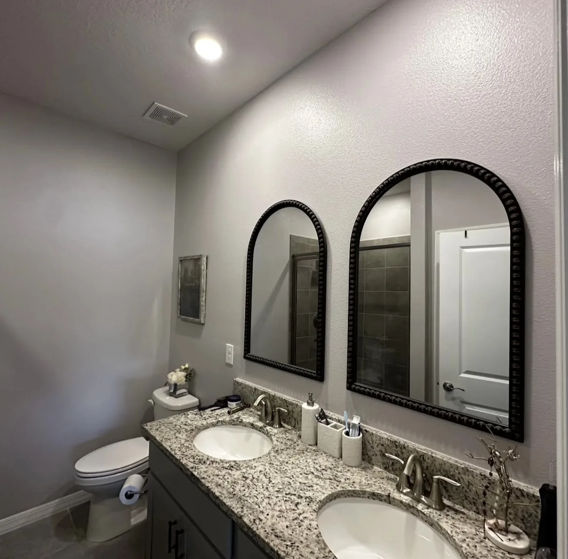Freshly painted bathroom in soft gray with dual vanity and arched mirrors by Bos-Flo Coatings