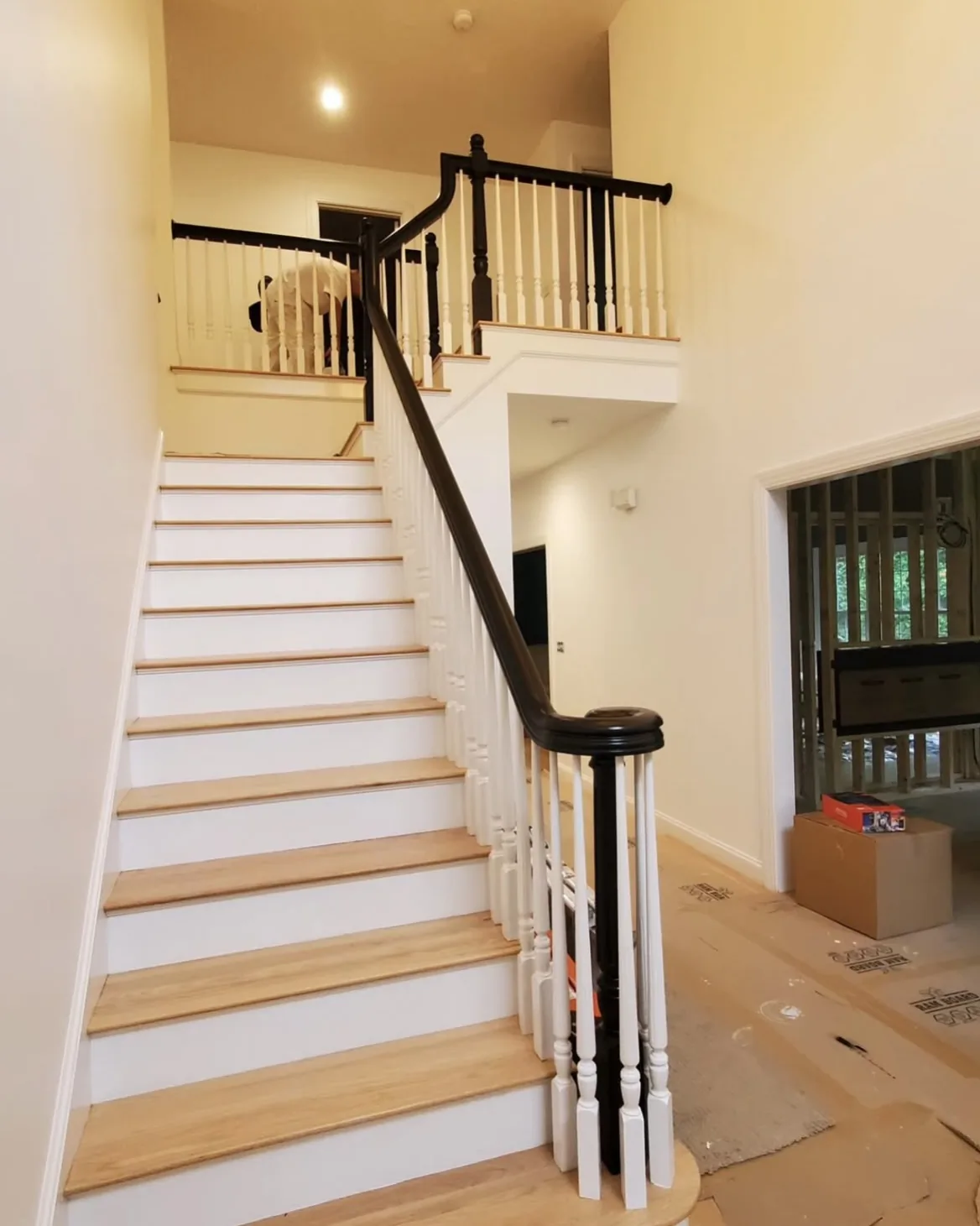 Freshly painted staircase with black handrail and white spindles and risers by Bos-Flo Coatings