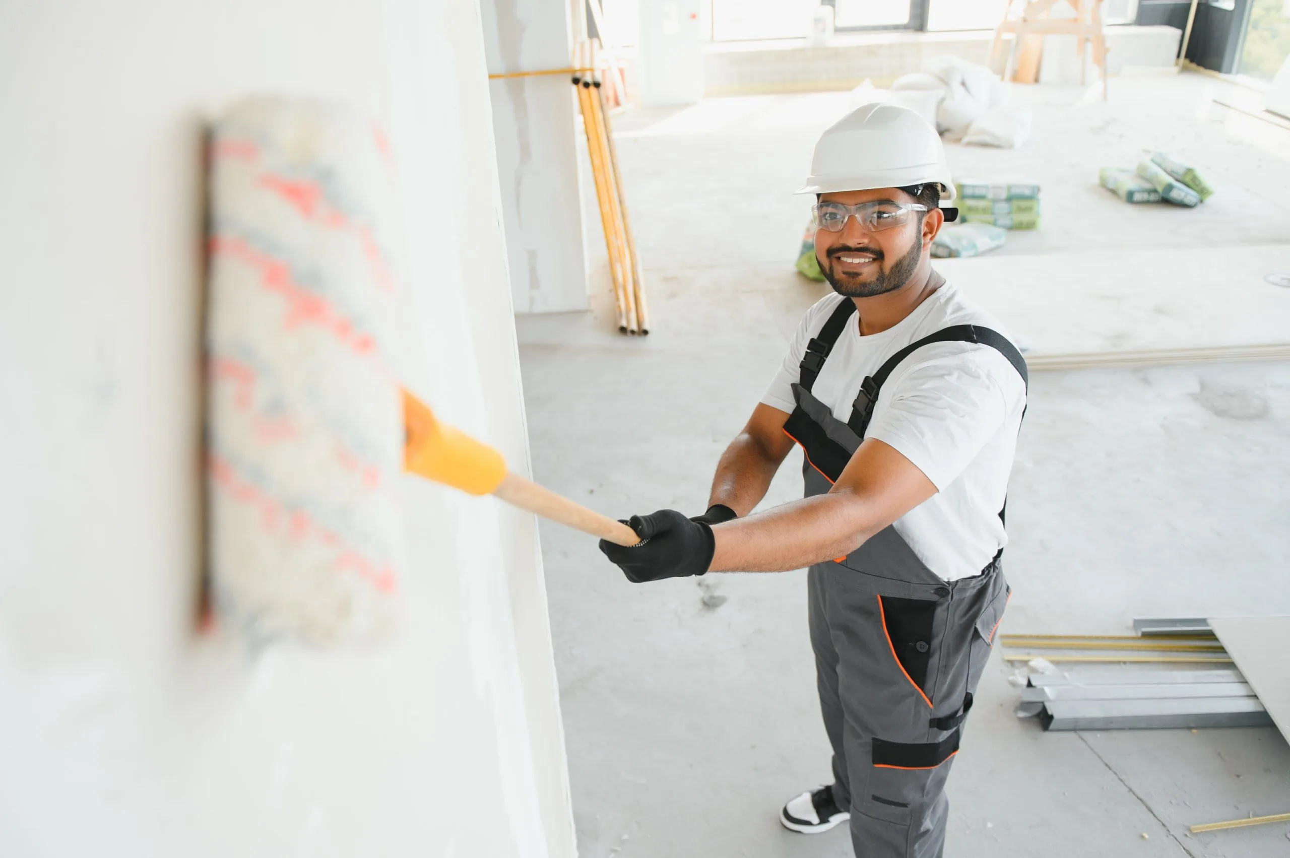 Professional painter applying white paint with roller on interior wall — Bos-Flo Coatings St. Petersburg