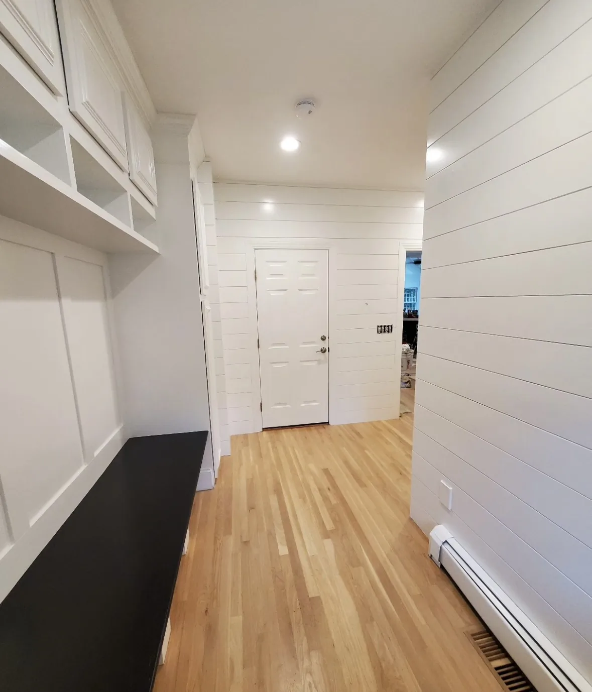 White painted built-in mudroom storage with glass-front cabinets and shiplap accent wall by Bos-Flo Coatings