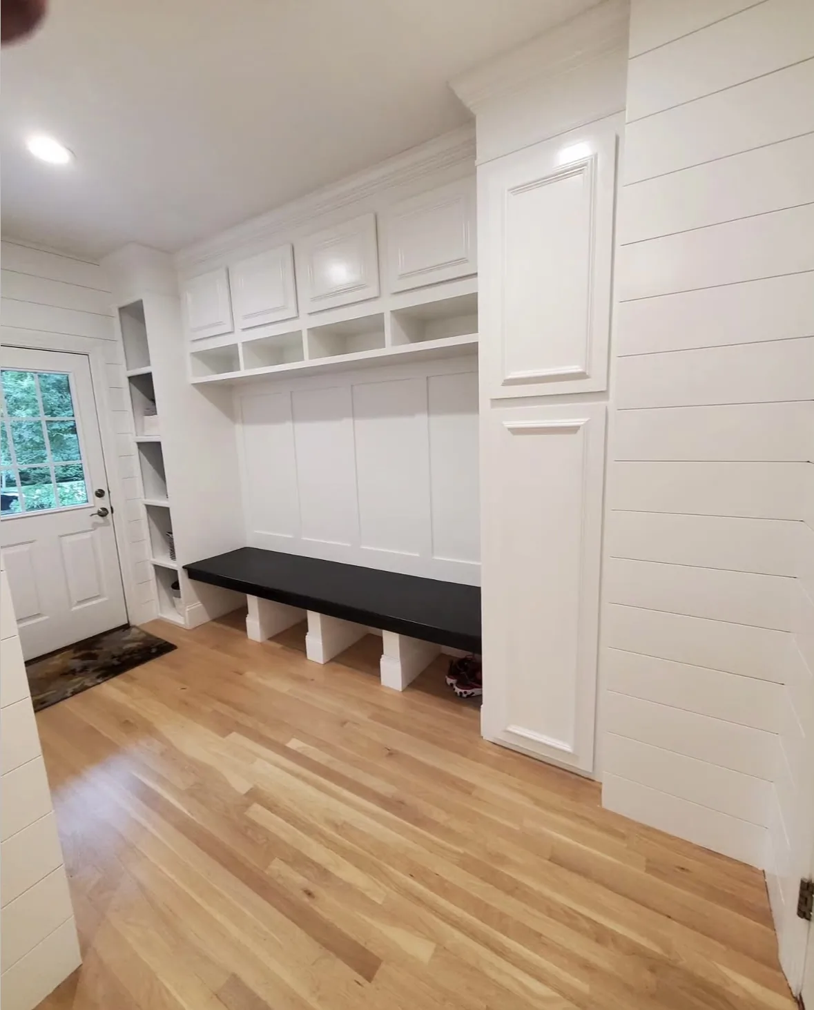 Professional white painted mudroom cabinets with shiplap walls and built-in bench by Bos-Flo Coatings