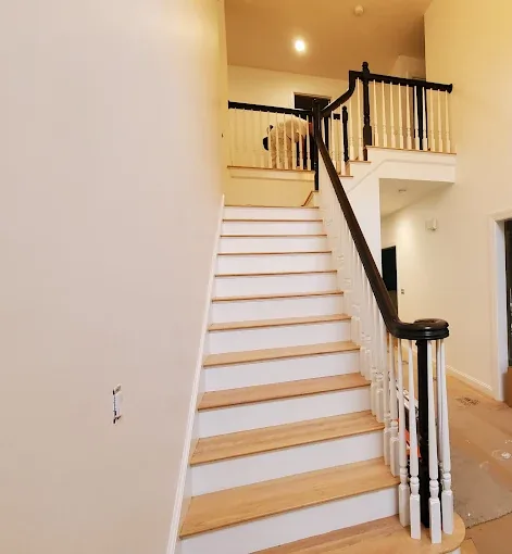Wooden staircase with white risers and dark handrail in a freshly painted interior hallway